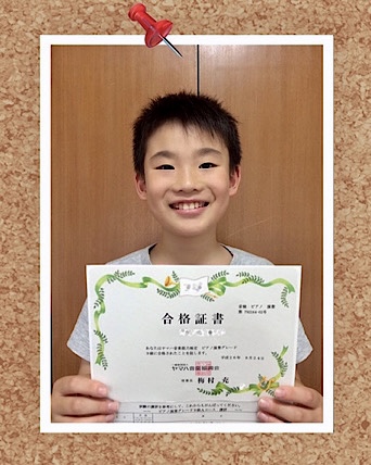 合格証を持って笑顔の福岡市南区「Chikaピアノ教室」に通う小学生の男の子の写真